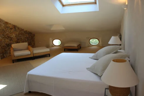 Bedroom 2 overlooking the 'Place', 'oil de boeuf' and Velux windows and exposed stone wall.