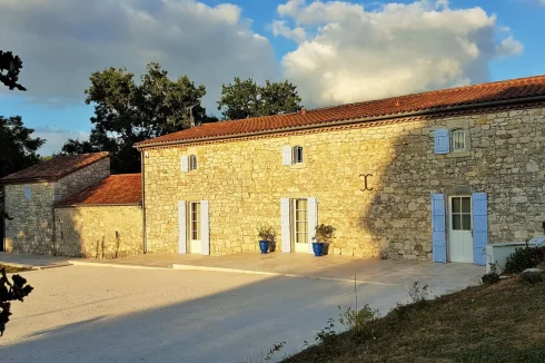 Façade ouest de la propriété avec son parking, son allée de fruitiers et sa terrasse éclairée