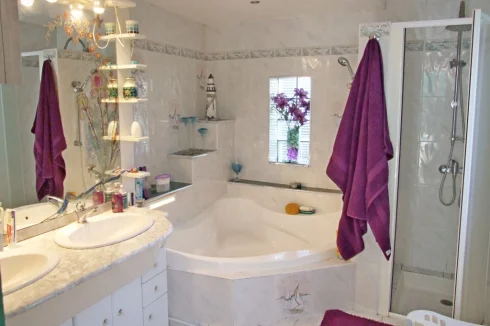 Tiled bathroom, corner bath with shower over, separate large shower cubicle, toilet and 2 basins