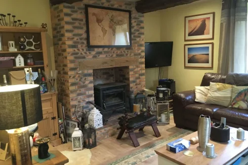 Dual aspect living room with stunning fireplace, woodburner, and large original beams